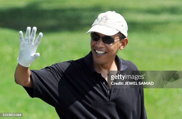 President Barack Obama waves at a crowd as he plays golf at the Farm Neck Golf Club in Oak Bluffs on Martha's Vineyard, Massachusetts, on August 24,...