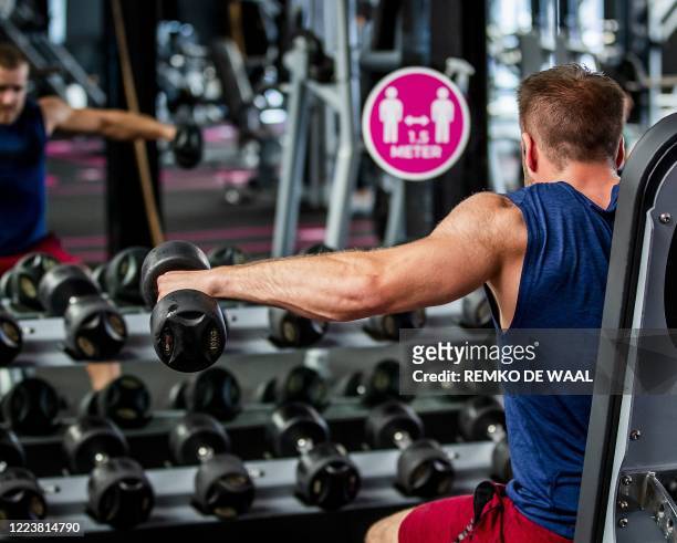 Cutomers lifts weights after fitness centres were authorised to reopen in the Netherlands with the easing of lockdown measures taken to curb the...