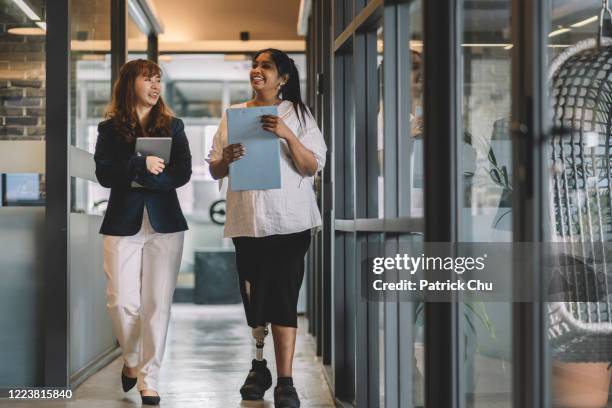 asiatische chinesische und indische amputierte geschäftsfrauen diskutieren im büro - amputee stock-fotos und bilder