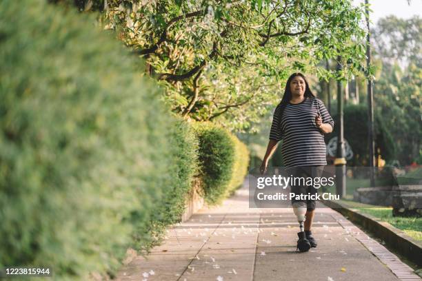 azië-indisch wijfje amputee met prothesebeen dat bij openbaar park uitoefent - amputatie stockfoto's en -beelden