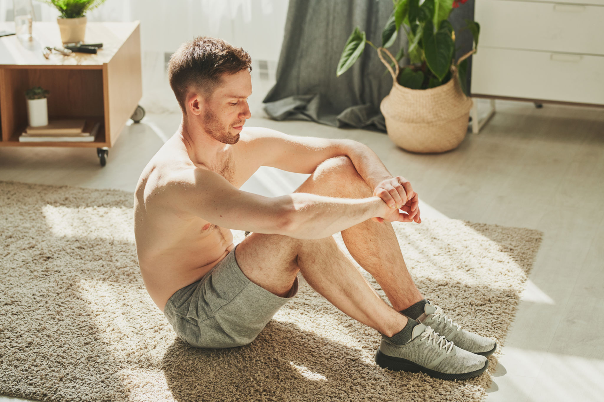 Shirtless athlete having rest on the floor of living-room after hard training Shirtless athlete having rest on the floor of living-room after hard training