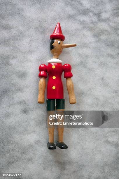 close up of wooden pinocchio figurine on gray marble table top. - pinocchio stock-fotos und bilder
