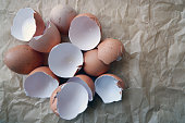 Broken chicken eggshells on brown background.