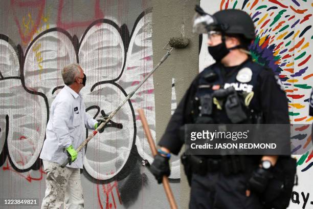 Worker paints over graffiti after police cleared the Capitol Hill Occupied Protest and retook the department's East Precinct in Seattle, Washington...