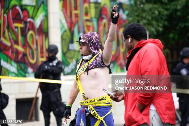 Demonstrator wrapped in police tape stands outside the Capitol Hill Occupied Protest after police cleared it and retook the department's East...