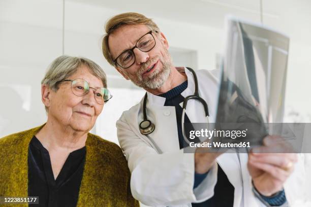 doctor discussing x-ray image with senior patient - male looking content stock pictures, royalty-free photos & images