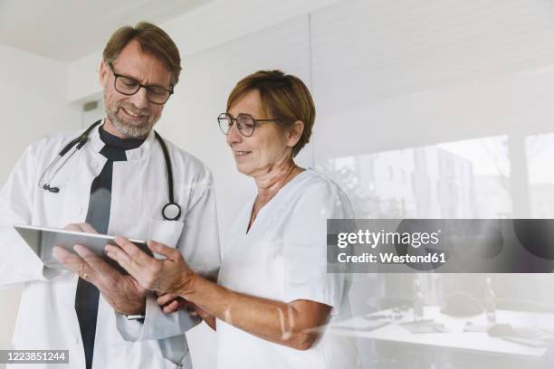 doctor and assistant using tablet in medical practice - 2 doctors stock-fotos und bilder