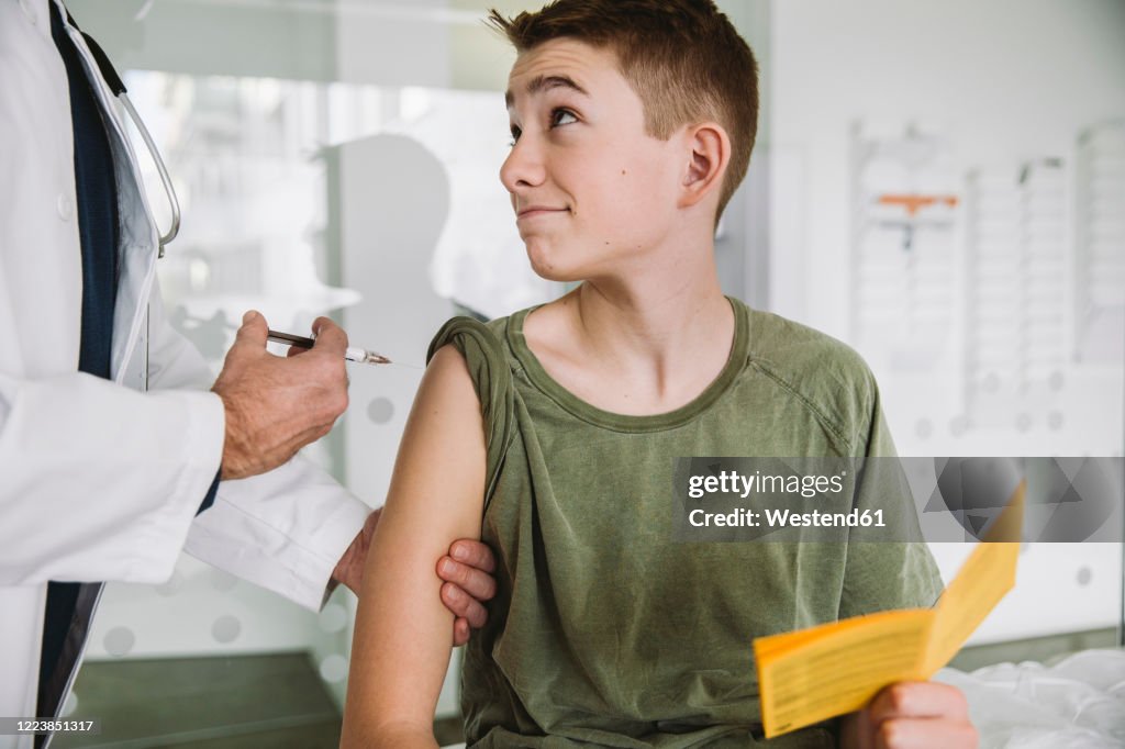 Doctor injecting a vaccine into teenager?s arm