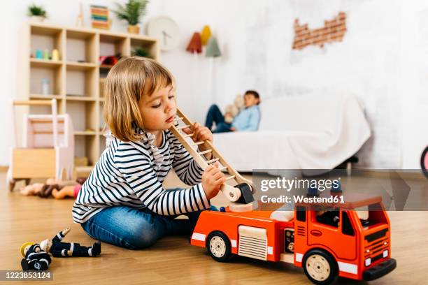 little blond playing with a wooden fire truck - boy toy stockfoto's en -beelden