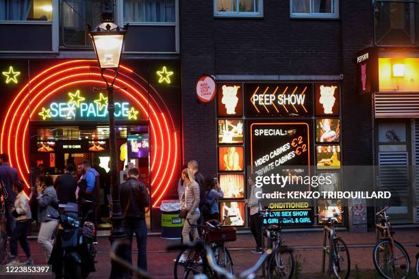 People walk in the red light district of Amsterdam on July 1 as Dutch brothels reopened today after a long coronavirus shutdown, with sex workers and...