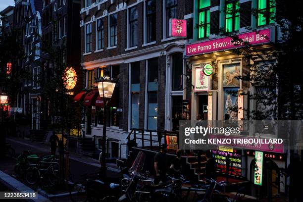 People walk in the red light district of Amsterdam on July 1 as Dutch brothels reopened today after a long coronavirus shutdown, with sex workers and...