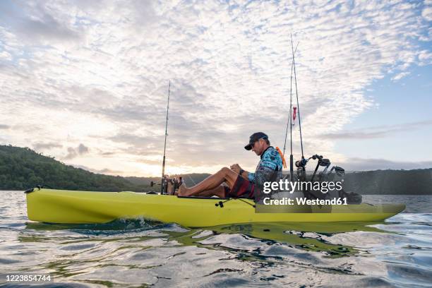 man in a kayak fishing in the pacific ocean at sunrise, costa rica - deep sea fishing stock-fotos und bilder