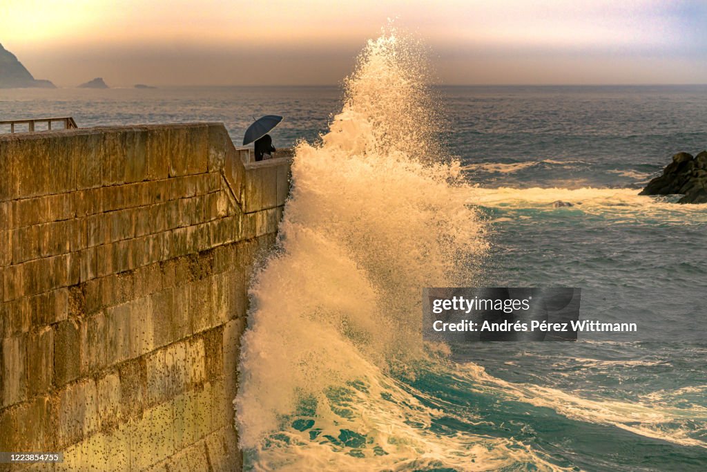 Woman with umbrella protects herself from giant wave