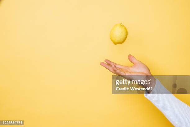 studio shot of hand of person tossing up lemon - throwing stock pictures, royalty-free photos & images