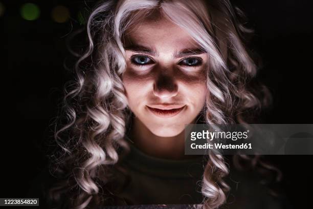 portrait of smiling young woman in darkness - face high contrast stock pictures, royalty-free photos & images