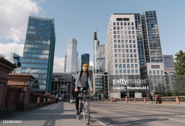 woman riding bicycle in the city, frankfurt, germany - hesse alemania fotografías e imágenes de stock