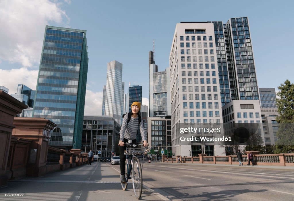 Woman riding bicycle in the city, Frankfurt, Germany