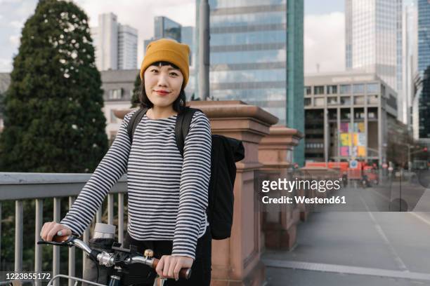 portrait of confident woman with bicycle in the city, frankfurt, germany - hesse germany stock-fotos und bilder