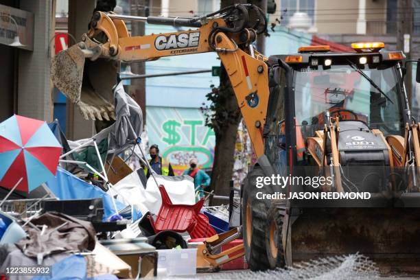 Workers use a bulldozer to remove remaining items from an encampment outside the Seattle Police Department's East Precinct after police cleared the...
