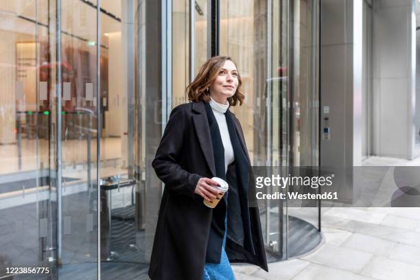 woman in the city coming out from revolving door, london, uk - revolving door foto e immagini stock