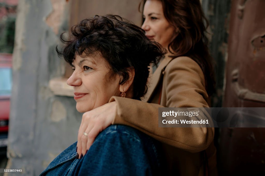 Smiling senior woman and her adult daughter in the background looking at distance