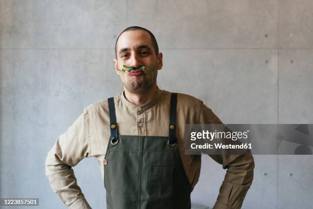portrait of man making nonsense with microgreen plant - grembiule foto e immagini stock