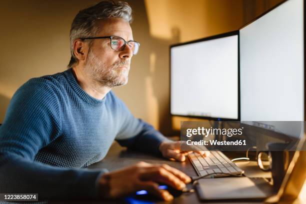mature man sitting at desk at home working on computer - staring at screen stock pictures, royalty-free photos & images