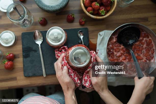 crop view of mother and little daughter preparing strawberry jam at home - marmeladenglas stock-fotos und bilder