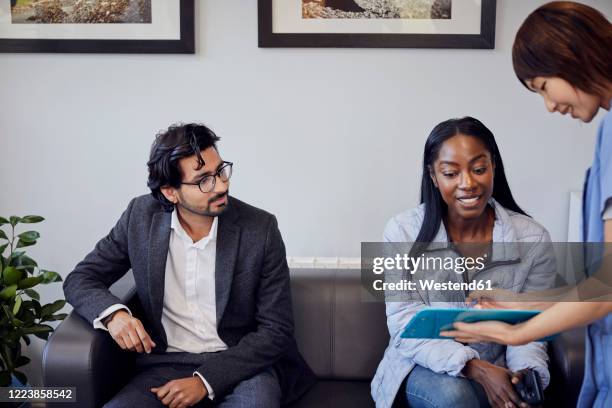 receptionist talking to patient in waiting room of a dental practice - dentist waiting room stock-fotos und bilder