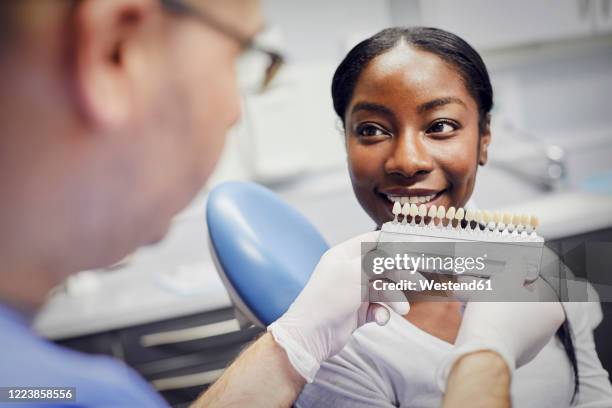 patient getting dental teeth whitening treatment - a male dentist stock pictures, royalty-free photos & images