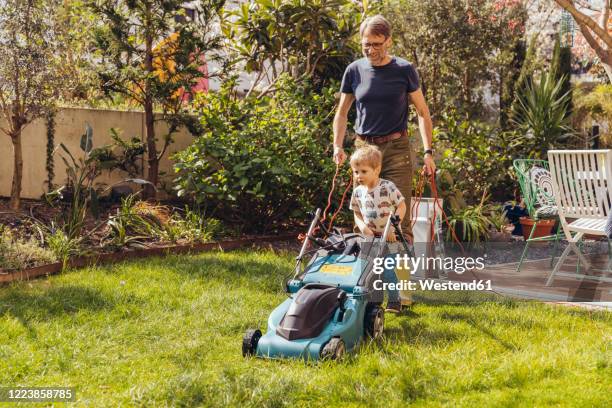 father and son mowing the lawn together - lawnmowing stock pictures, royalty-free photos & images