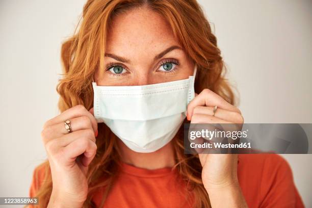 portrait of red-haired woman wearing a face mask at home - female surgeon mask - fotografias e filmes do acervo