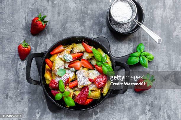 pan of kaiserschmarrn with strawberries, powdered sugar and basil - kaiserschmarrn stock pictures, royalty-free photos & images