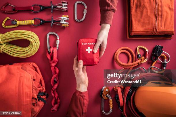 overhead view of woman handing over first aid kit to man with climbing equipment in background - woman climbing rope stock-fotos und bilder