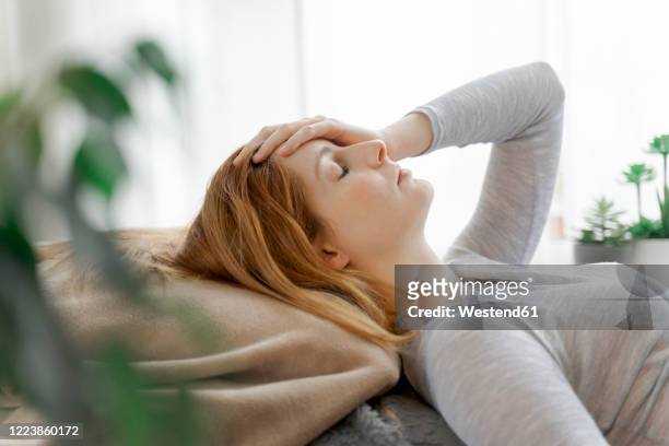 serious young woman at home lying down - langes haar stock-fotos und bilder