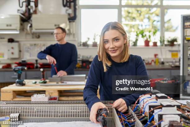 portrait of smiling female electrician working on circuitry in workshop - schaltschrank stock-fotos und bilder
