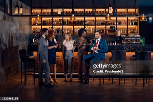 friends socializing at the counter in a bar - formele kleding stockfoto's en -beelden