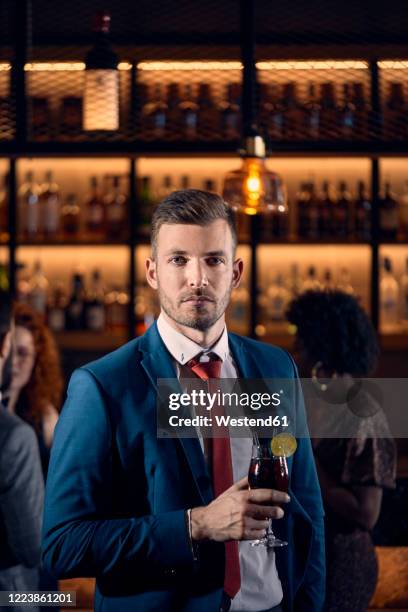 portrait of a serious young man having a cocktail in a bar - arrogant man stock pictures, royalty-free photos & images