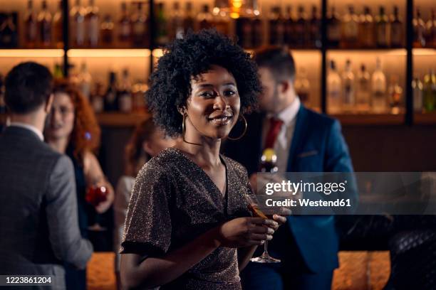 portrait of a young woman having a cocktail in a bar - cocktail dress stock-fotos und bilder