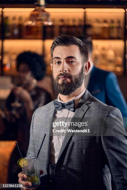portrait of a young man having a cocktail in a bar - 蝶ネクタイ ストックフォトと画像