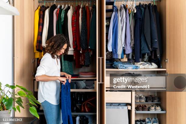 woman clearing out her wardrobe - vestuario fotografías e imágenes de stock