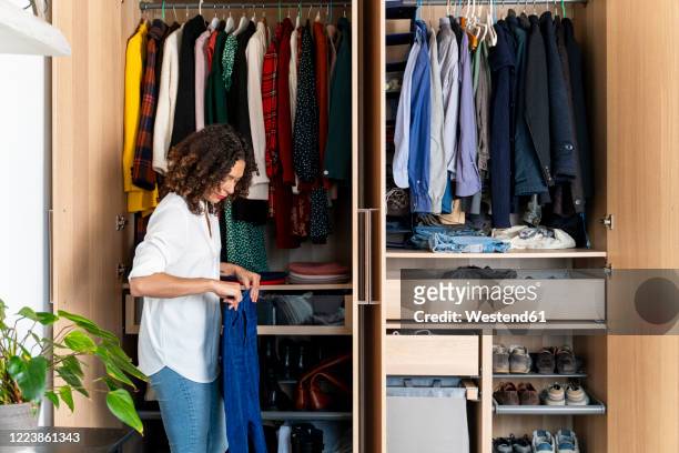 woman clearing out her wardrobe - organisatie stockfoto's en -beelden