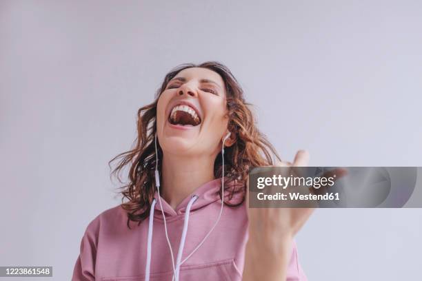 brunette woman listening to music and singing - hoodie headphones stock pictures, royalty-free photos & images