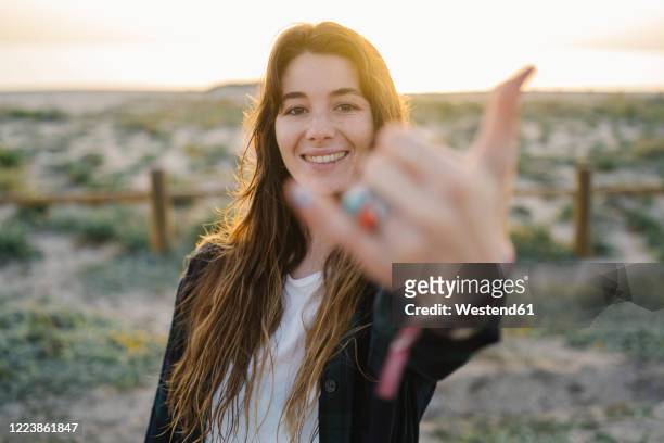 portrait of smiling young woman  showing shaka sign - shaka sign stock-fotos und bilder