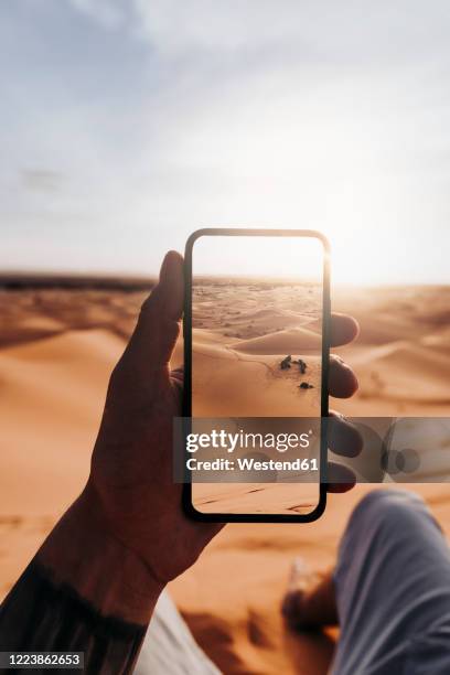 hand holding smartphone with foto of the desert - fotohandy stock pictures, royalty-free photos & images