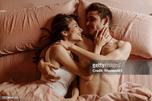 happy young couple lying in bed - two men in bed cuddling stock-fotos und bilder