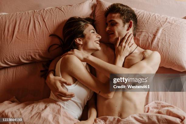 happy young couple lying in bed - 性的行動 ストックフォトと画像