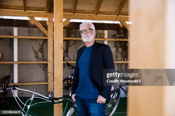 portrait of senior man sitting with racing cycle standing in a shelter - three quarter length stock pictures, royalty-free photos & images