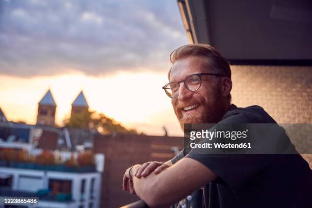 portrait of relaxed man on balcony looking at distance - golden hour stock pictures, royalty-free photos & images