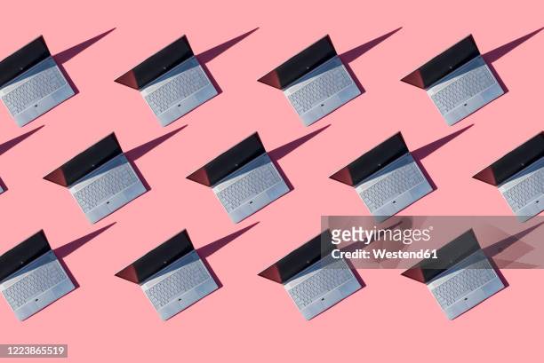 laptops on pink background - ripetizione foto e immagini stock